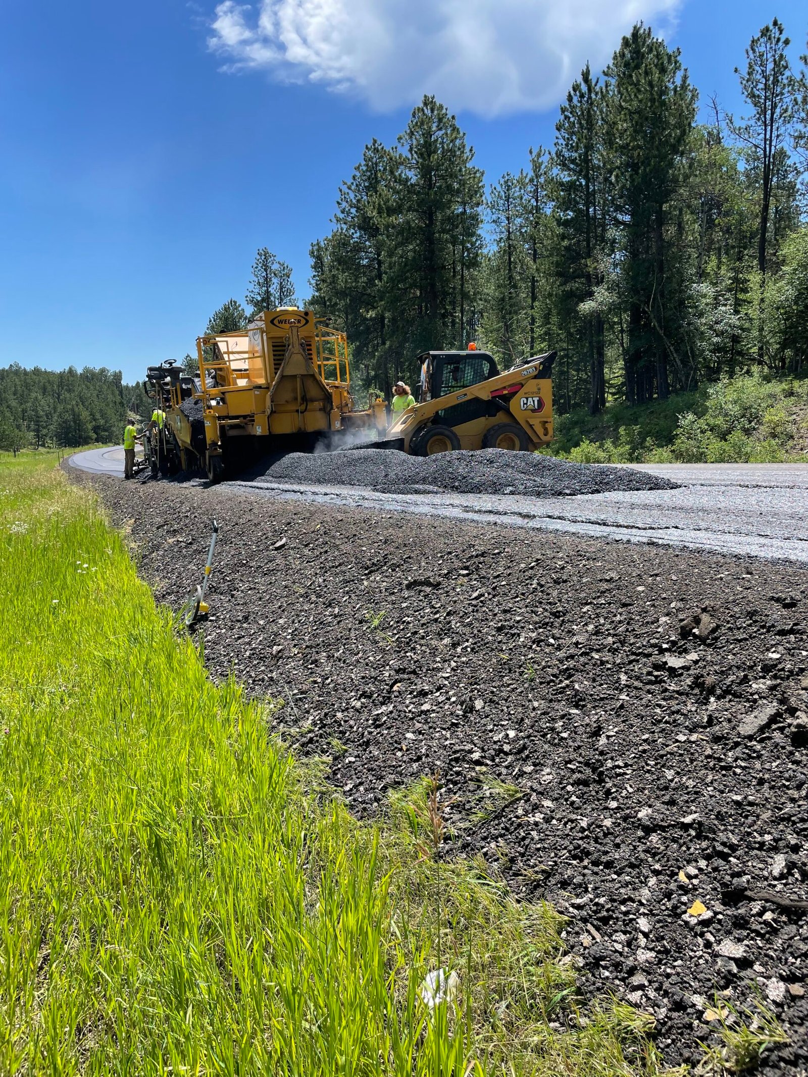 Skid-steer adjusting asphalt material